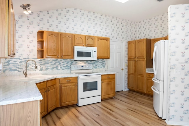 kitchen featuring sink, light hardwood / wood-style floors, vaulted ceiling, white appliances, and decorative backsplash