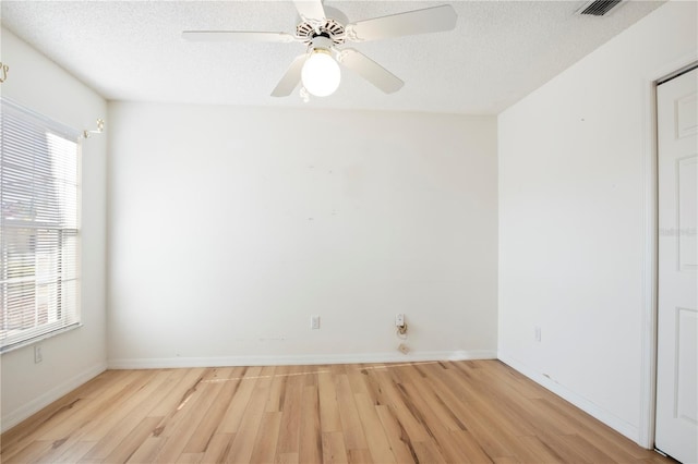 spare room with a healthy amount of sunlight, light hardwood / wood-style floors, and a textured ceiling