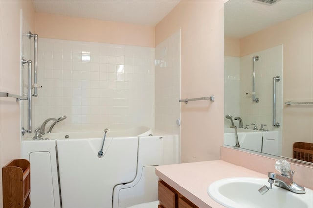 bathroom featuring a washtub, a textured ceiling, and vanity