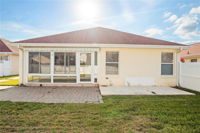 rear view of property with a lawn, a patio area, and a sunroom