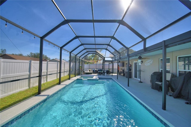 view of pool featuring glass enclosure, a patio area, and ceiling fan