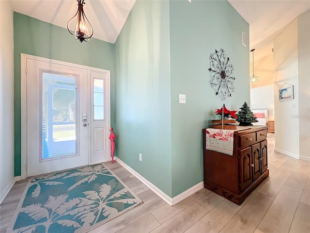 entrance foyer featuring a chandelier, lofted ceiling, and light hardwood / wood-style flooring