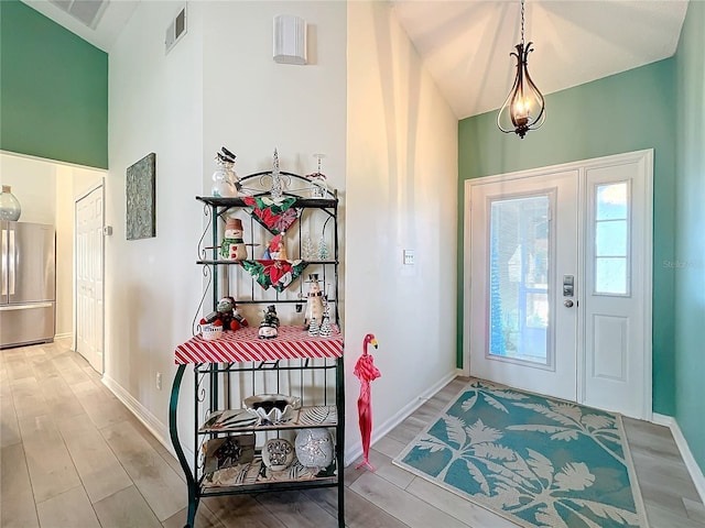 foyer with light hardwood / wood-style floors and vaulted ceiling