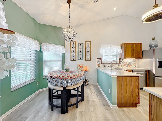 dining room with light wood-type flooring, lofted ceiling, a healthy amount of sunlight, and sink