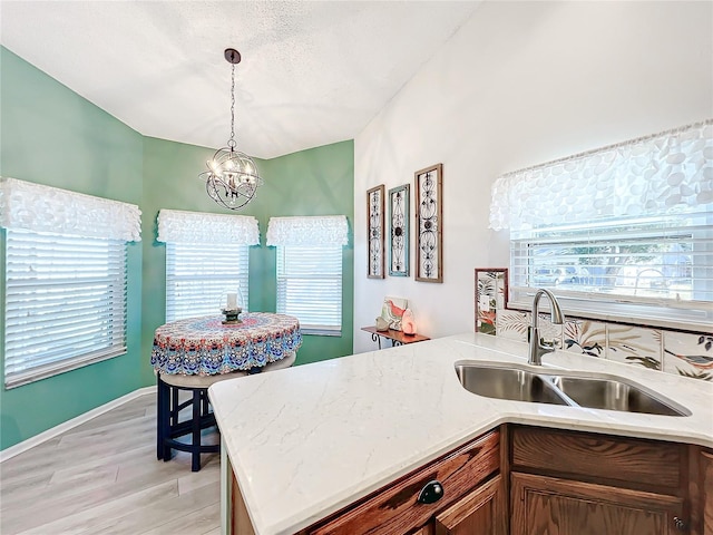 kitchen featuring decorative light fixtures, light hardwood / wood-style floors, an inviting chandelier, and sink