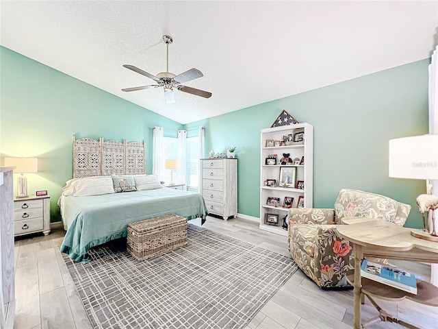 bedroom with a textured ceiling, vaulted ceiling, light hardwood / wood-style flooring, and ceiling fan