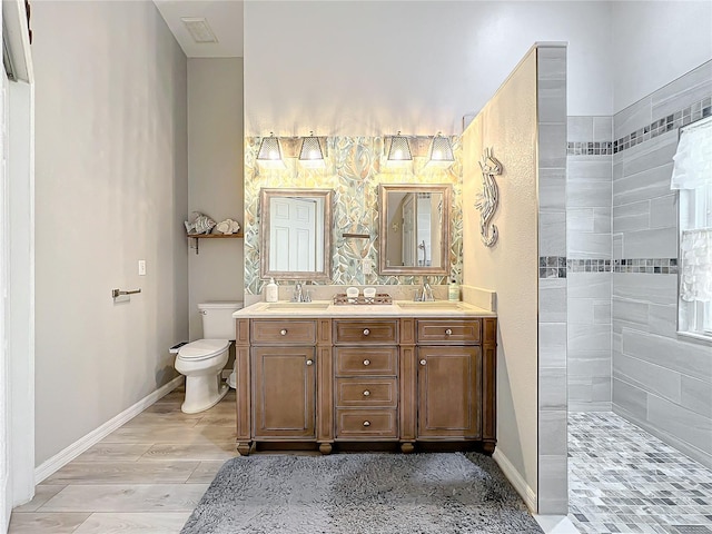 bathroom featuring tiled shower, wood-type flooring, vanity, and toilet