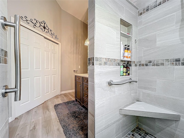 bathroom featuring hardwood / wood-style floors, vanity, and tiled shower