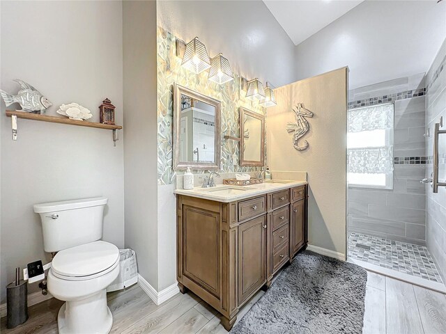 bathroom featuring toilet, hardwood / wood-style floors, vanity, and tiled shower