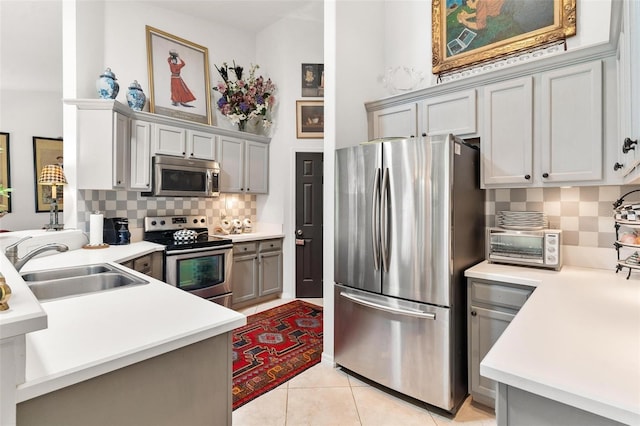 kitchen with gray cabinetry, sink, decorative backsplash, light tile patterned flooring, and stainless steel appliances