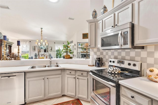 kitchen featuring sink, a notable chandelier, backsplash, light tile patterned floors, and appliances with stainless steel finishes