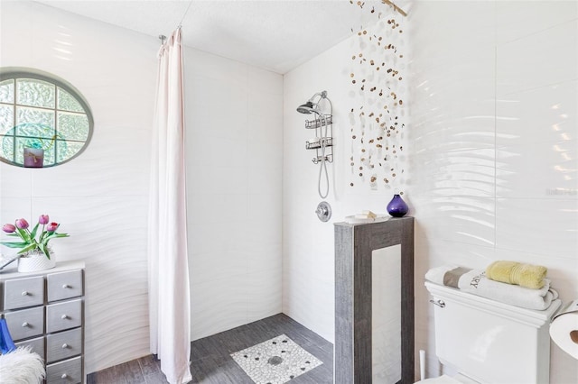 bathroom featuring hardwood / wood-style flooring, toilet, tile walls, and tiled shower