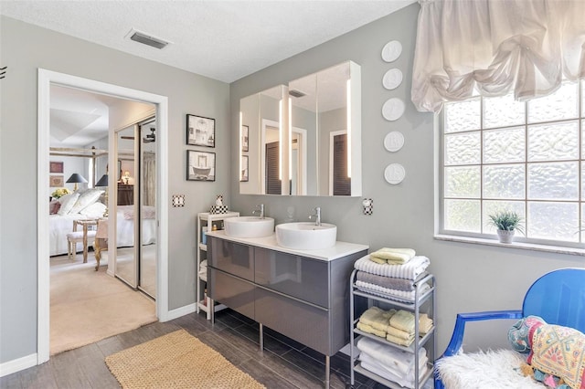 bathroom with hardwood / wood-style floors, vanity, and a textured ceiling