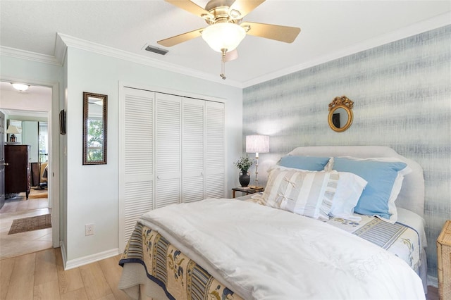 bedroom featuring ceiling fan, light hardwood / wood-style floors, crown molding, and a closet