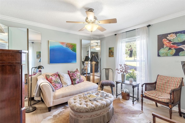 living area featuring ceiling fan, light hardwood / wood-style flooring, a textured ceiling, and ornamental molding