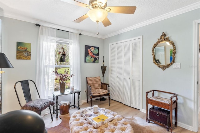 sitting room featuring a textured ceiling, ceiling fan, light wood-type flooring, and crown molding