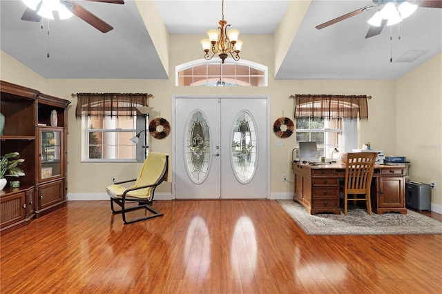 foyer entrance featuring wood-type flooring, ceiling fan with notable chandelier, vaulted ceiling, and french doors