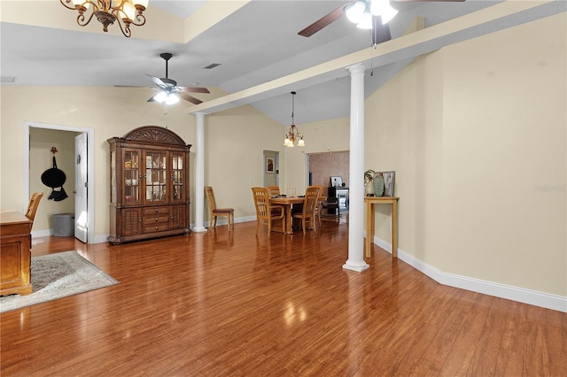 interior space featuring wood-type flooring, ceiling fan with notable chandelier, decorative columns, and high vaulted ceiling