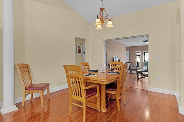 dining room featuring hardwood / wood-style floors, ceiling fan with notable chandelier, and decorative columns