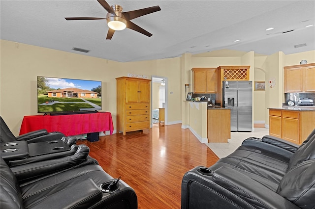 living room featuring a textured ceiling, light hardwood / wood-style flooring, and ceiling fan