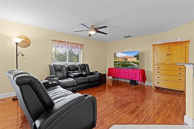 living room featuring a textured ceiling, light hardwood / wood-style flooring, and ceiling fan