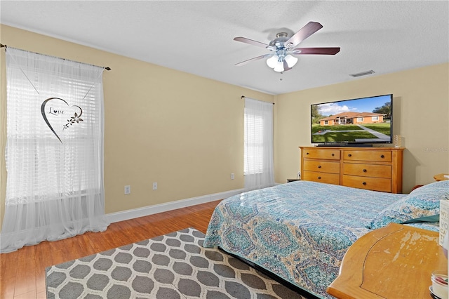 bedroom with wood-type flooring, a textured ceiling, and ceiling fan