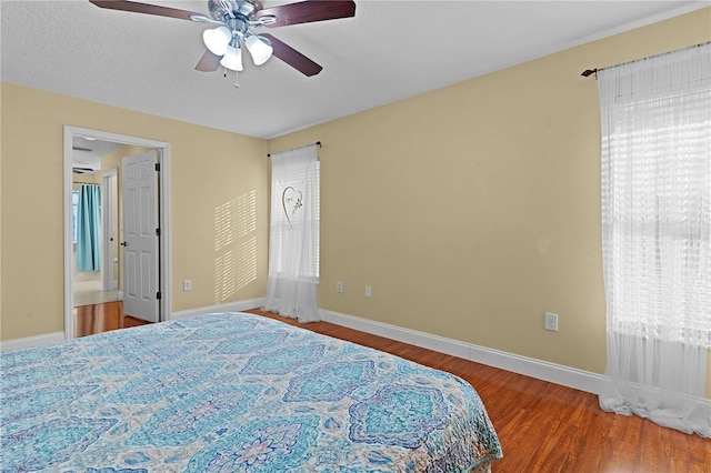 bedroom with multiple windows, hardwood / wood-style floors, and ceiling fan