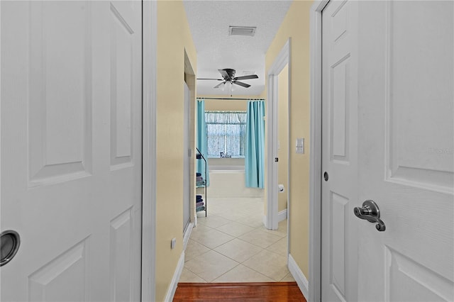 hallway with light tile patterned floors and a textured ceiling