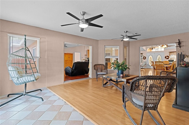 living room with hardwood / wood-style floors, ceiling fan, and a textured ceiling