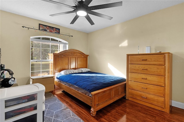 bedroom with a textured ceiling, ceiling fan, and dark wood-type flooring