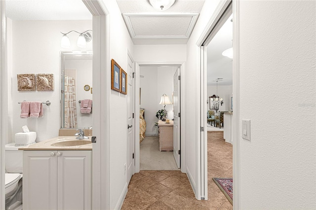 hallway featuring sink, light tile patterned flooring, and a textured ceiling