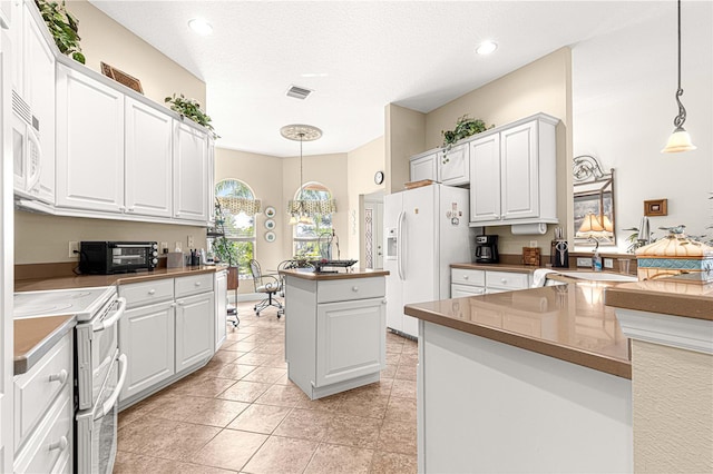 kitchen with white cabinets, sink, white appliances, and hanging light fixtures