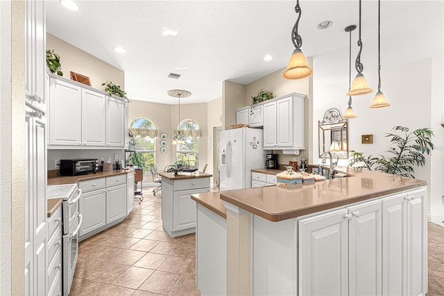 kitchen featuring a center island with sink, electric range, white cabinets, and white fridge with ice dispenser