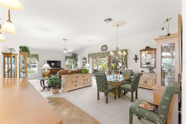 tiled dining area with ceiling fan with notable chandelier and vaulted ceiling