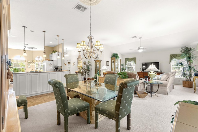 dining room with lofted ceiling, light colored carpet, and ceiling fan with notable chandelier