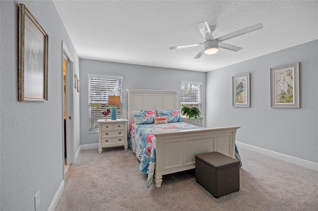 bedroom featuring a textured ceiling, light colored carpet, and ceiling fan