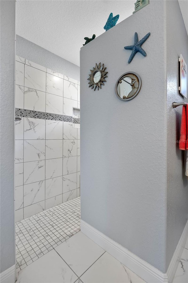 bathroom featuring a tile shower and a textured ceiling