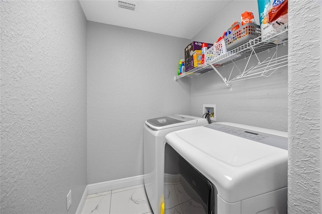 clothes washing area with a textured ceiling and washing machine and clothes dryer