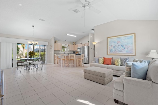 living area featuring light tile patterned floors, vaulted ceiling, and ceiling fan with notable chandelier