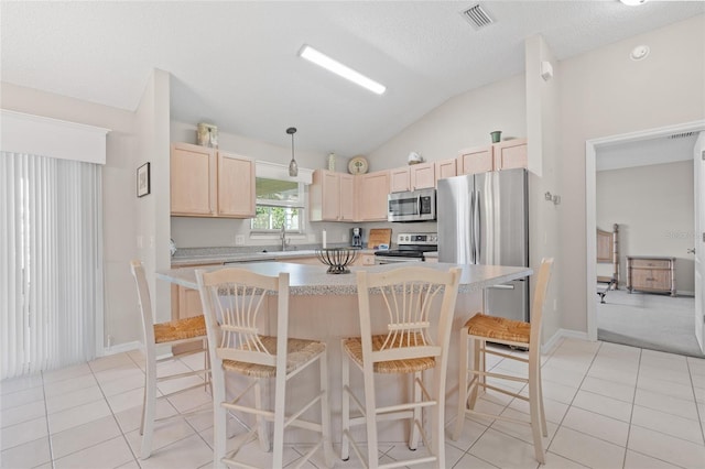 kitchen featuring stainless steel appliances, light countertops, visible vents, light brown cabinets, and vaulted ceiling