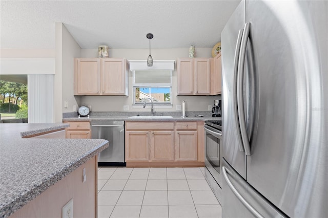 kitchen with light tile patterned floors, light brown cabinetry, appliances with stainless steel finishes, and a sink