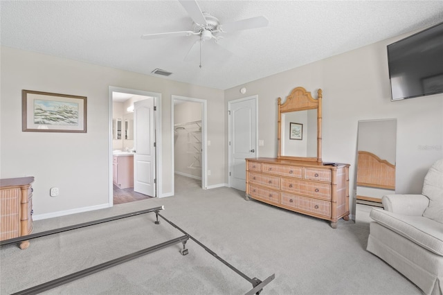 bedroom with a walk in closet, visible vents, a textured ceiling, and carpet flooring