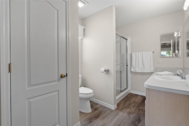 bathroom with toilet, a shower stall, a textured ceiling, and wood finished floors