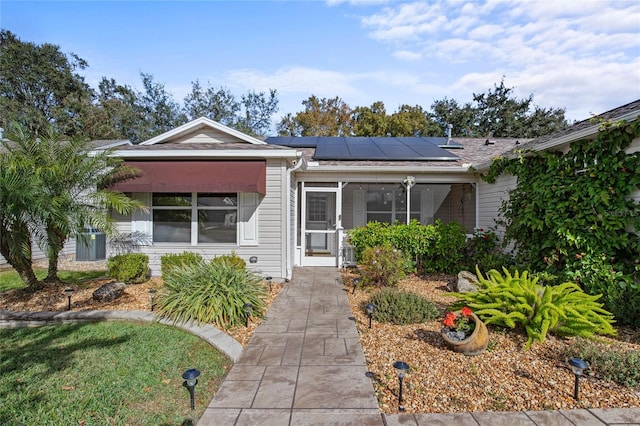 single story home featuring solar panels and a sunroom