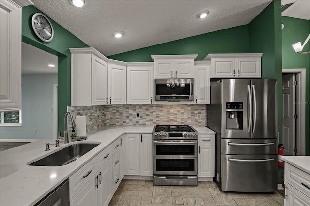 kitchen featuring white cabinets, tasteful backsplash, lofted ceiling, and appliances with stainless steel finishes