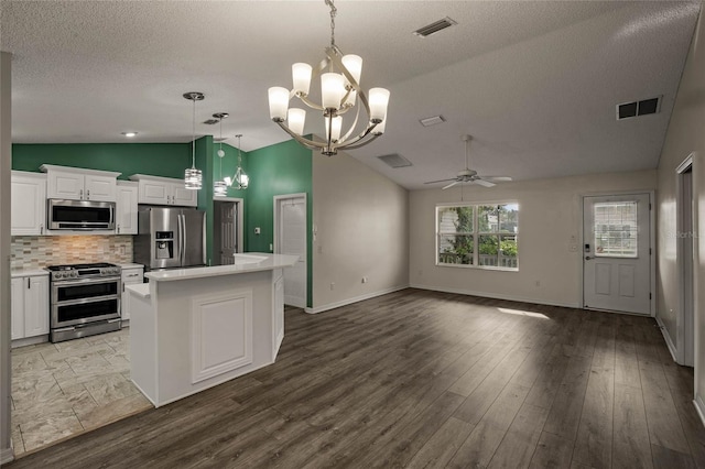 kitchen with a center island, tasteful backsplash, white cabinetry, decorative light fixtures, and stainless steel appliances