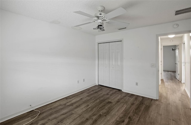 unfurnished bedroom featuring a closet, ceiling fan, a textured ceiling, and dark hardwood / wood-style flooring