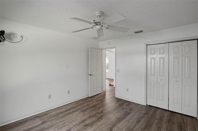 unfurnished bedroom with ceiling fan, a textured ceiling, dark hardwood / wood-style floors, and a closet