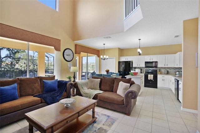 tiled living room with a towering ceiling, plenty of natural light, and a notable chandelier