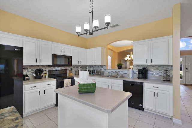 kitchen featuring decorative backsplash, white cabinetry, a center island, and black appliances